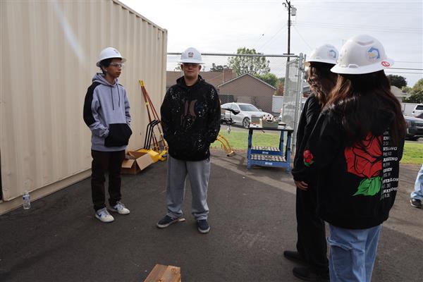 Wood shop students working on the construction site trying to complete the framing of the floor before the rain hits.