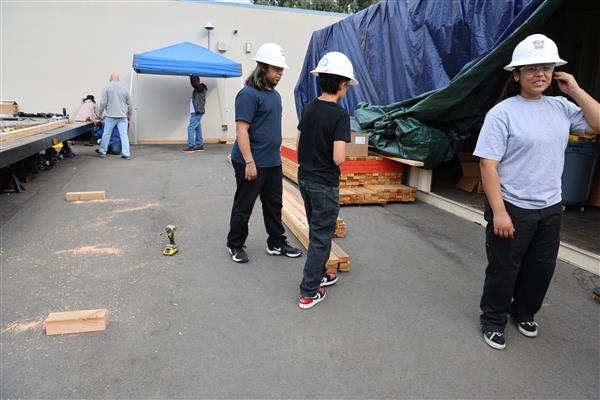 Wood shop students working on the construction site trying to complete the framing of the floor before the rain hits.