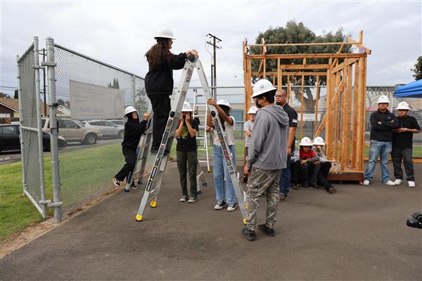 Wood shop students working on the construction site trying to complete the framing of the floor before the rain hits.