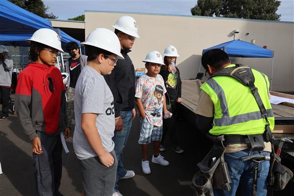 Wood shop students working on the construction site trying to complete the framing of the floor before the rain hits.