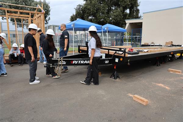 Wood shop students working on the construction site trying to complete the framing of the floor before the rain hits.