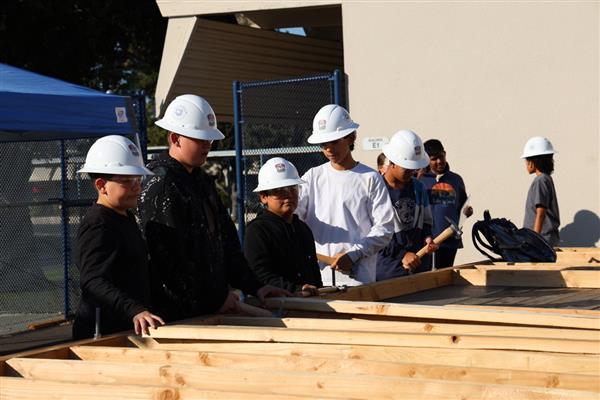 Wood shop students working on laying the floor boards.