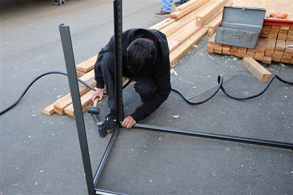 Students building shelving for the storage container to organize materials.