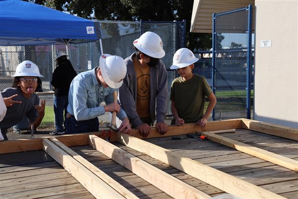 Wood shop students working on laying the floor boards.