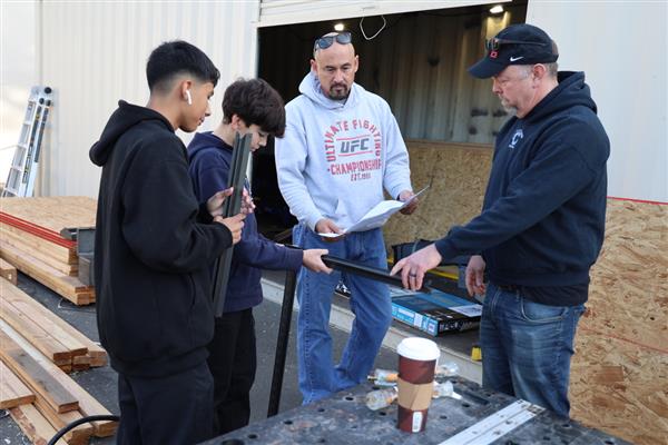 Students building shelving for the storage container to organize materials.