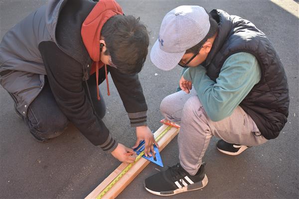 Measuring the wood and using the saw to cut it for the framing.