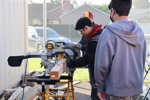 Using the saw to cut wood for the framing.