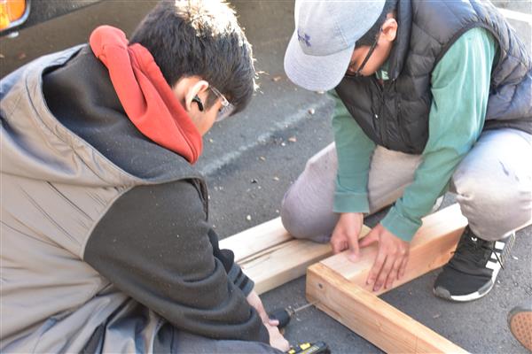 Measuring the wood and using the saw to cut it for the framing.