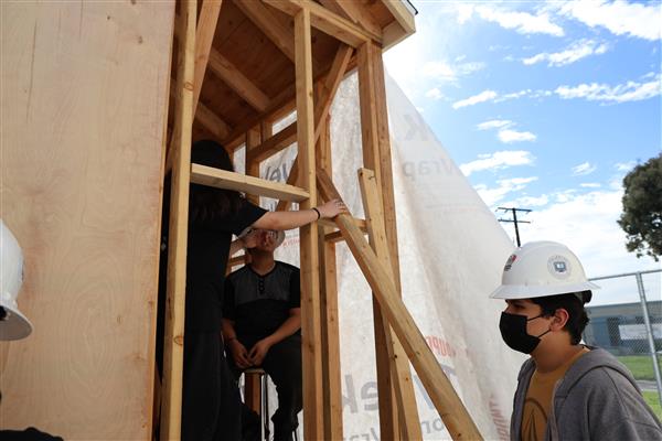 Students installing the moisture barrier to protect the wood of the structure.