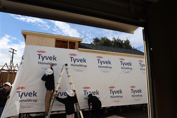 Students installing the moisture barrier to protect the wood of the structure.