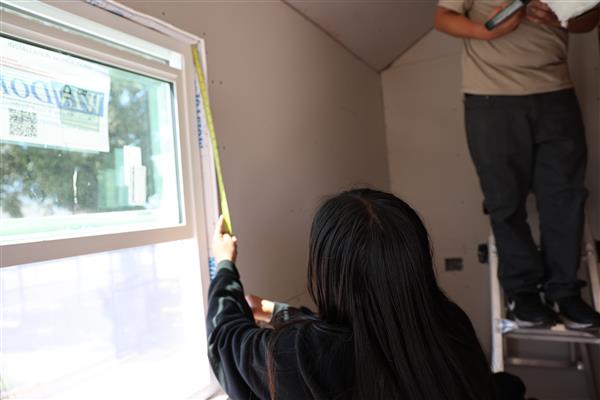 Student measuring the window for framing.