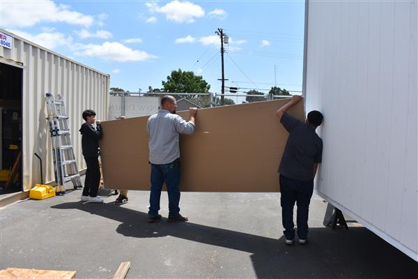 Students measuring and cutting drywall to be installed. 