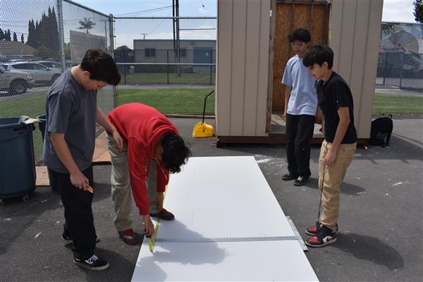 Students measuring and cutting drywall to be installed. 