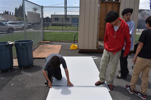 Students measuring and cutting drywall to be installed. 