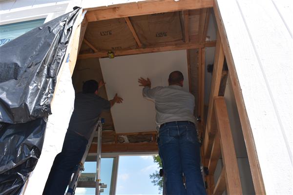 Installing drywall on the ceiling.