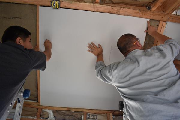 Installing drywall on the ceiling.